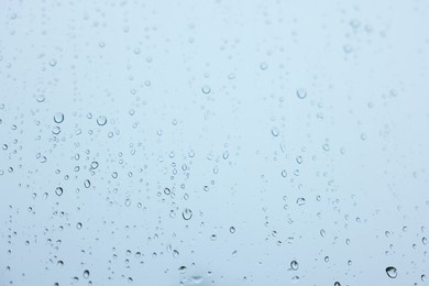 View on sky through window with water droplets on rainy day, closeup