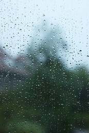 Photo of View on buildings through window with water droplets on rainy day, closeup