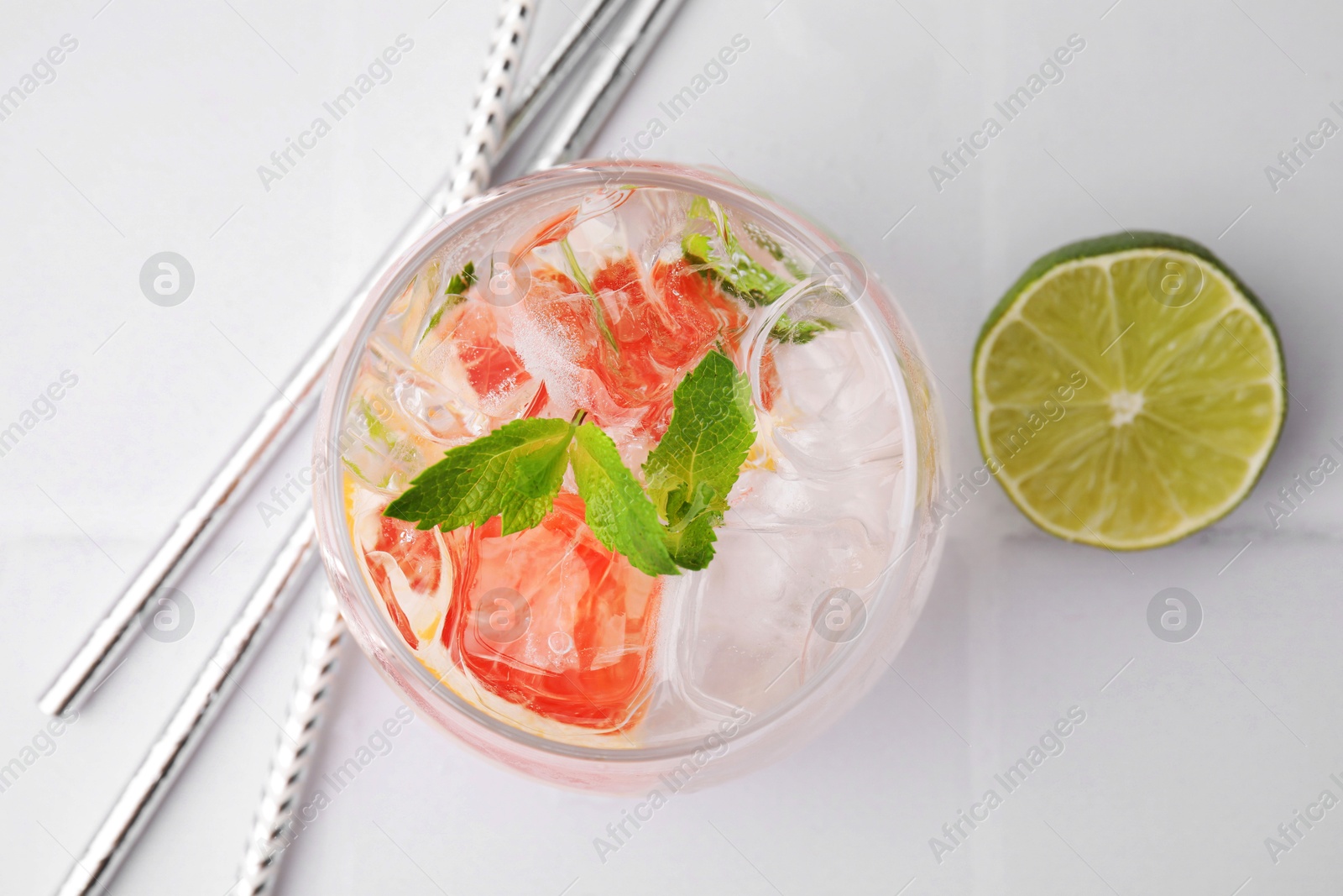 Photo of Refreshing water with grapefruit and mint in glass on white tiled table, flat lay