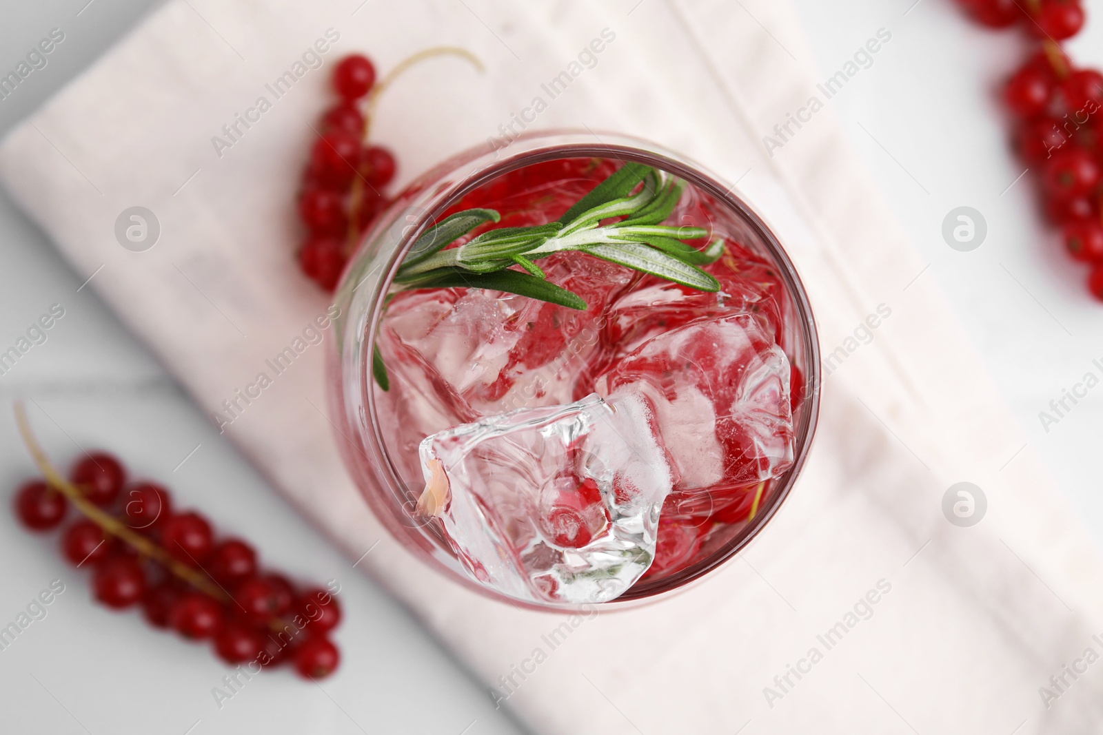 Photo of Refreshing water with red currants and rosemary in glass on white table, top view