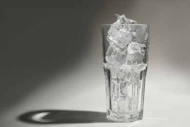 Photo of One glass with ice for refreshing drink on grey background