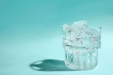 Photo of Refreshing water with ice in glass on turquoise background. Space for text