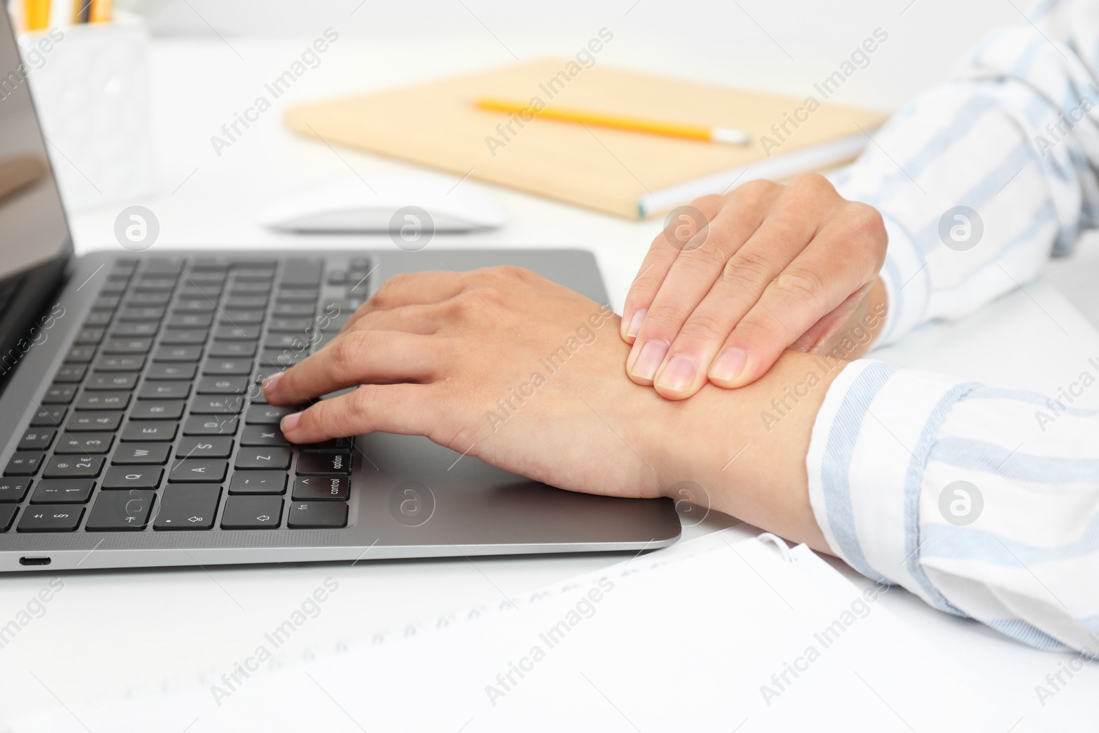 Photo of Carpal tunnel syndrome. Woman suffering from pain in wrist at desk, closeup