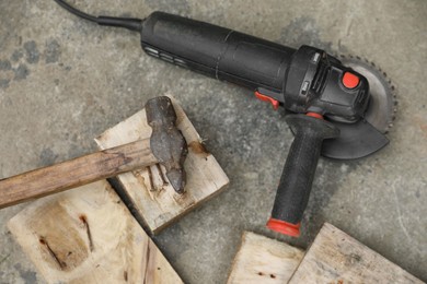 Photo of Angle grinder, hammer and wooden planks on asphalt outdoors, top view