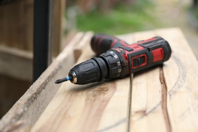 Photo of Electric screwdriver on wooden plank outdoors, closeup