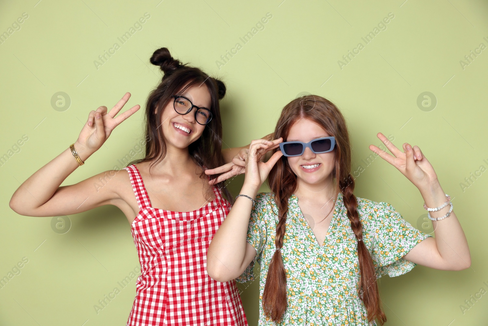 Photo of Happy teenage girls showing peace signs on green background