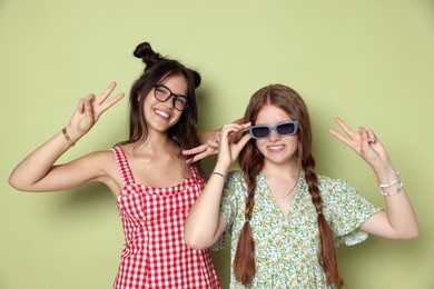 Photo of Happy teenage girls showing peace signs on green background