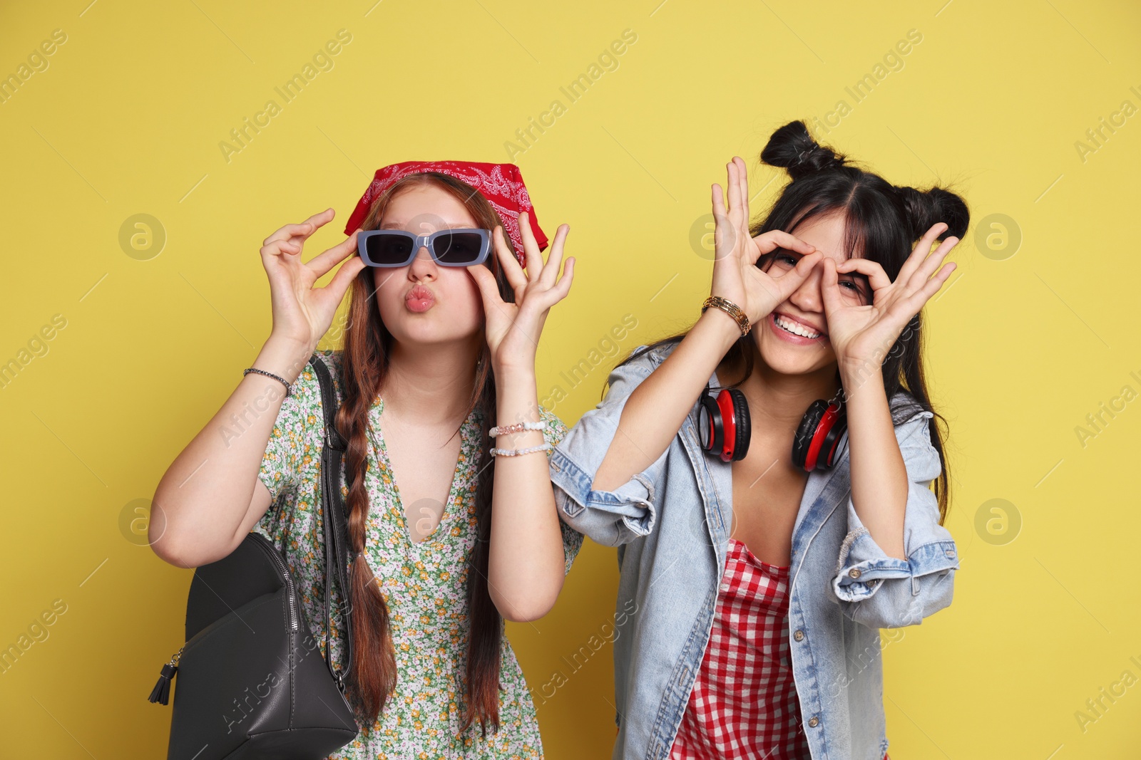 Photo of Funny teenage girls posing on yellow background