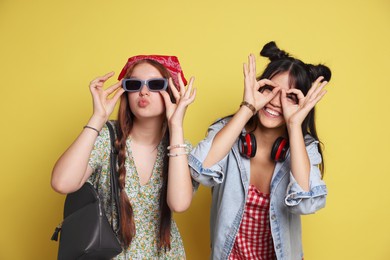 Photo of Funny teenage girls posing on yellow background