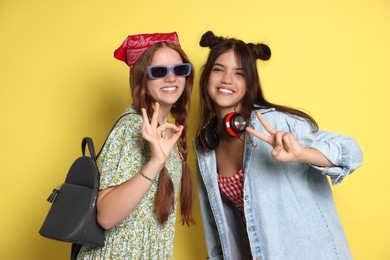 Photo of Happy teenage girls posing on yellow background