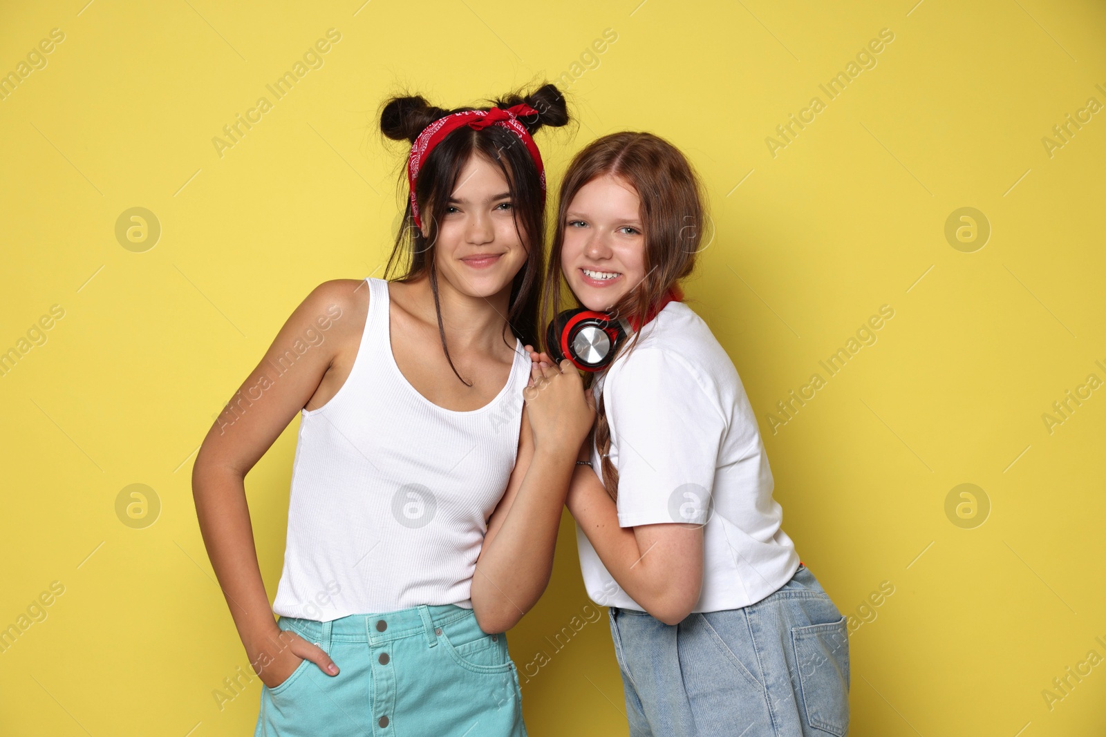 Photo of Happy teenage girls posing on yellow background