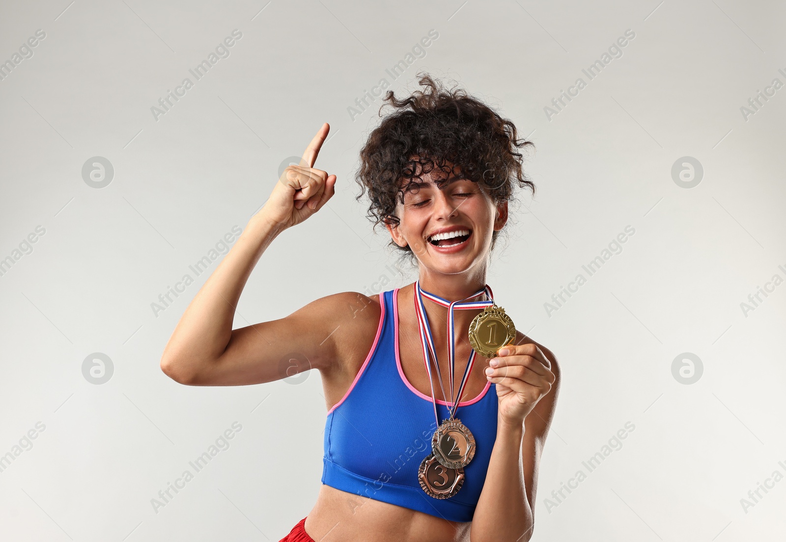 Photo of Happy winner with different medals upwards on light grey background