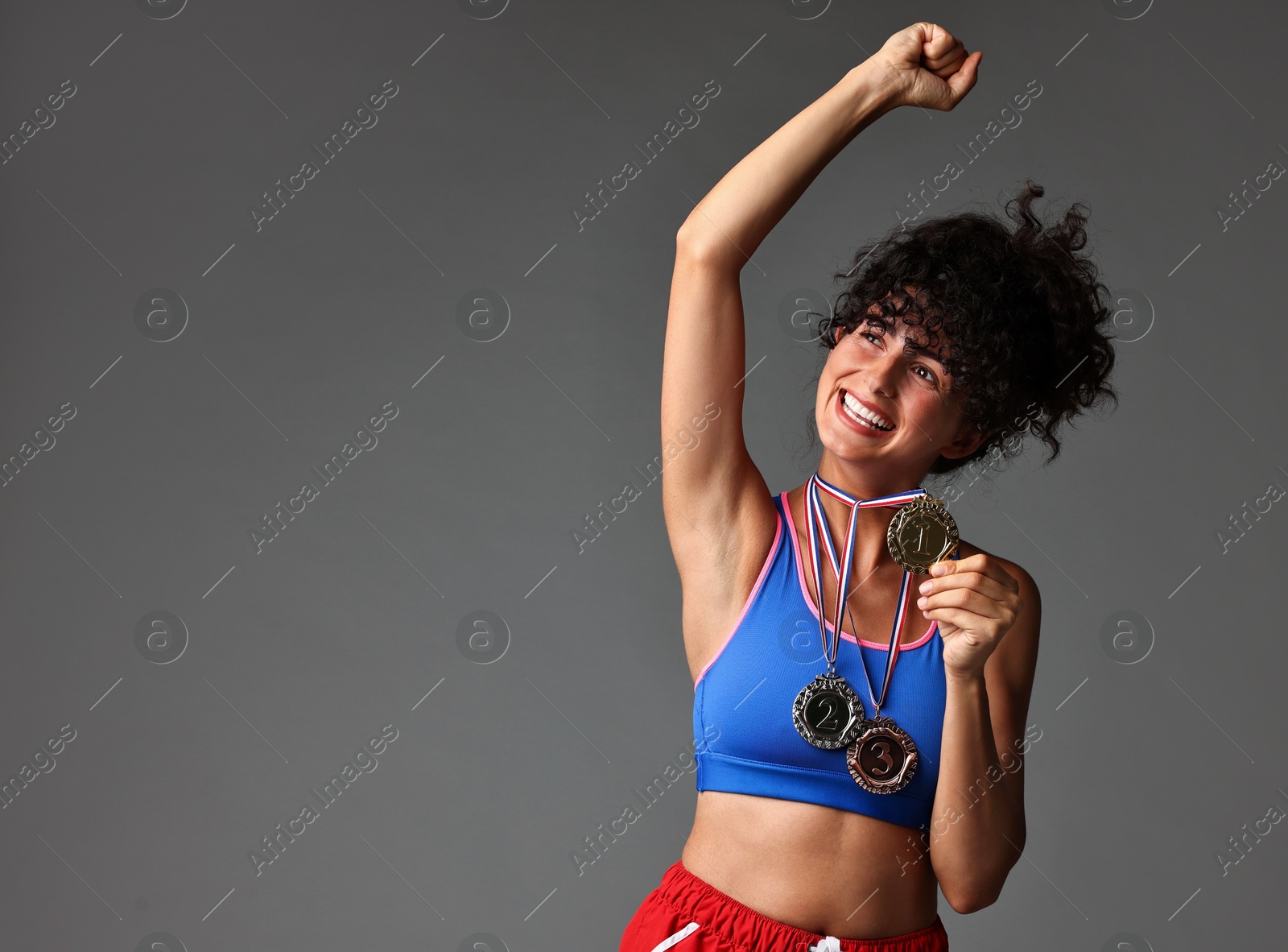 Photo of Happy winner with different medals on grey background. Space for text