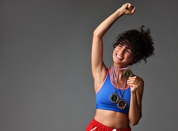 Happy winner with different medals on grey background. Space for text