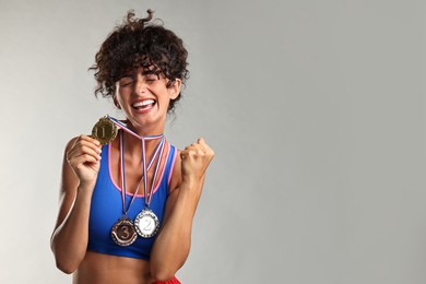 Photo of Happy winner with different medals on light grey background. Space for text