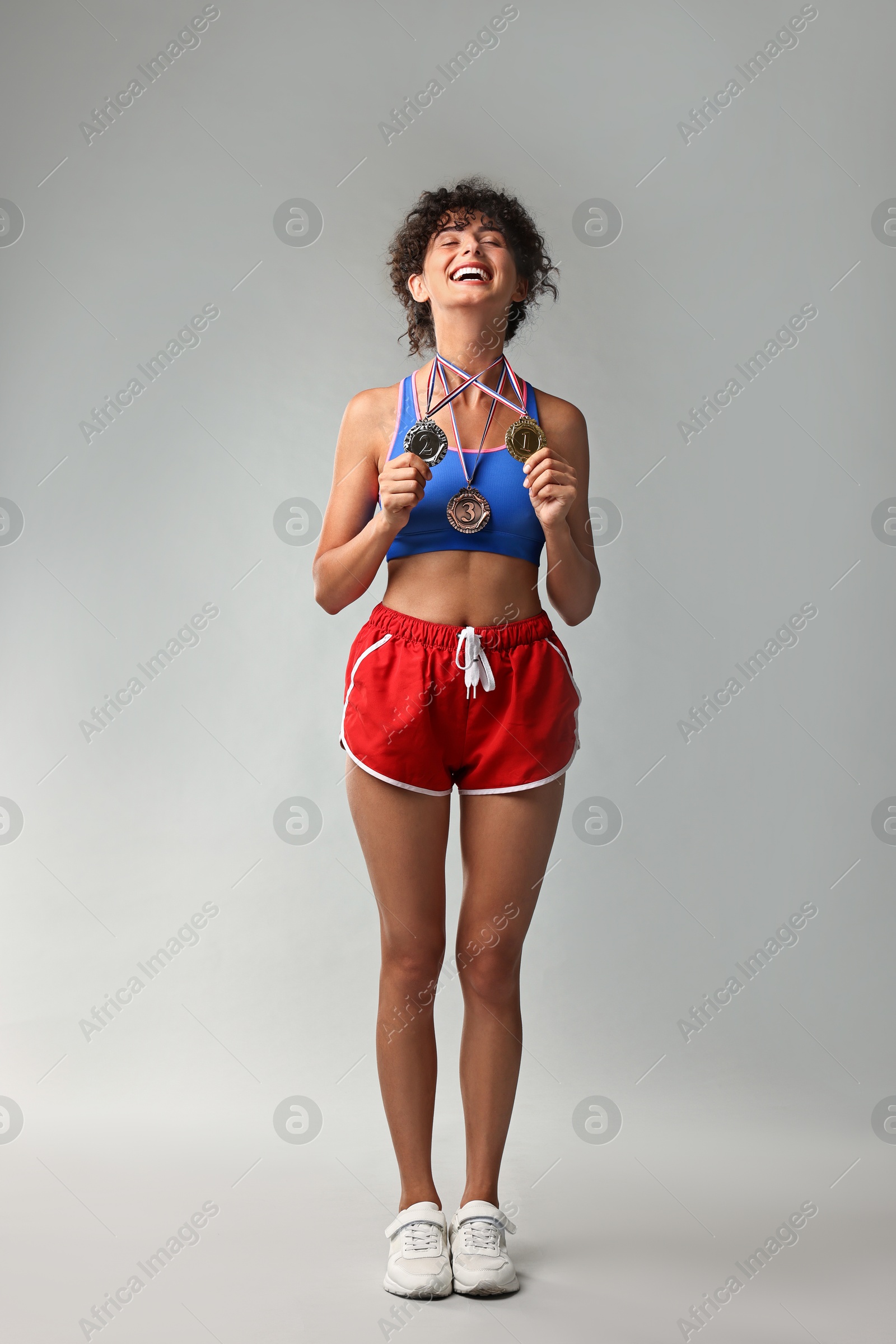 Photo of Happy winner with different medals on light grey background