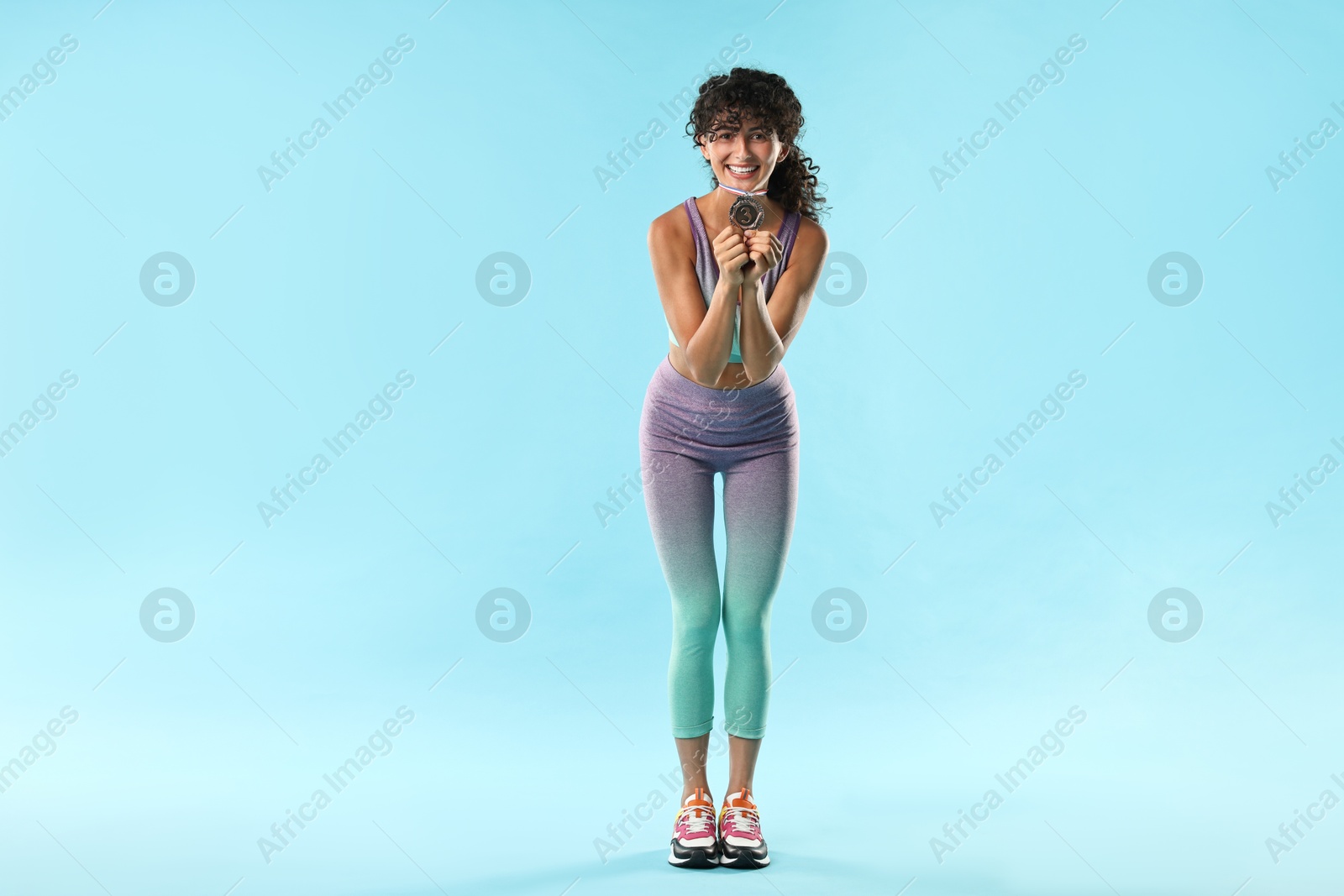 Photo of Happy winner with bronze medal on light blue background