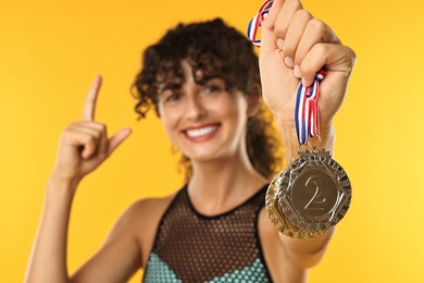 Photo of Happy winner showing different medals on yellow background, selective focus