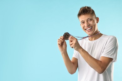 Photo of Happy winner with bronze medal on light blue background. Space for text