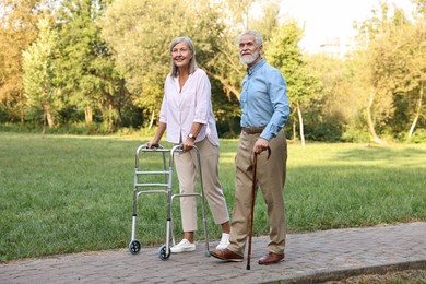 Senior couple with walking frame and cane in park