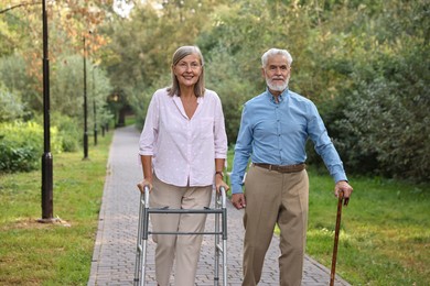 Senior couple with walking frame and cane in park