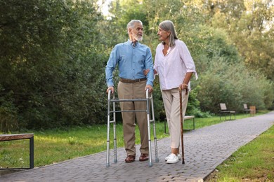 Senior couple with walking frame and cane in park