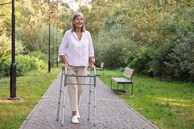 Photo of Senior woman with walking frame in park, space for text