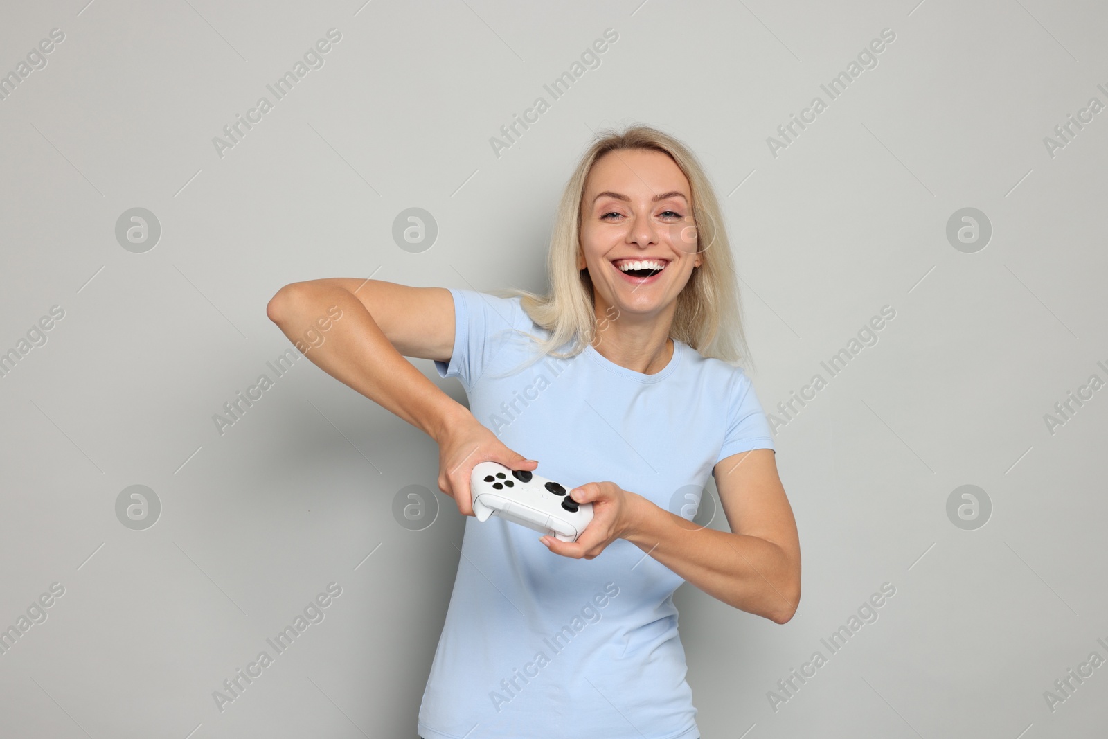 Photo of Happy woman playing video games with controller on gray background