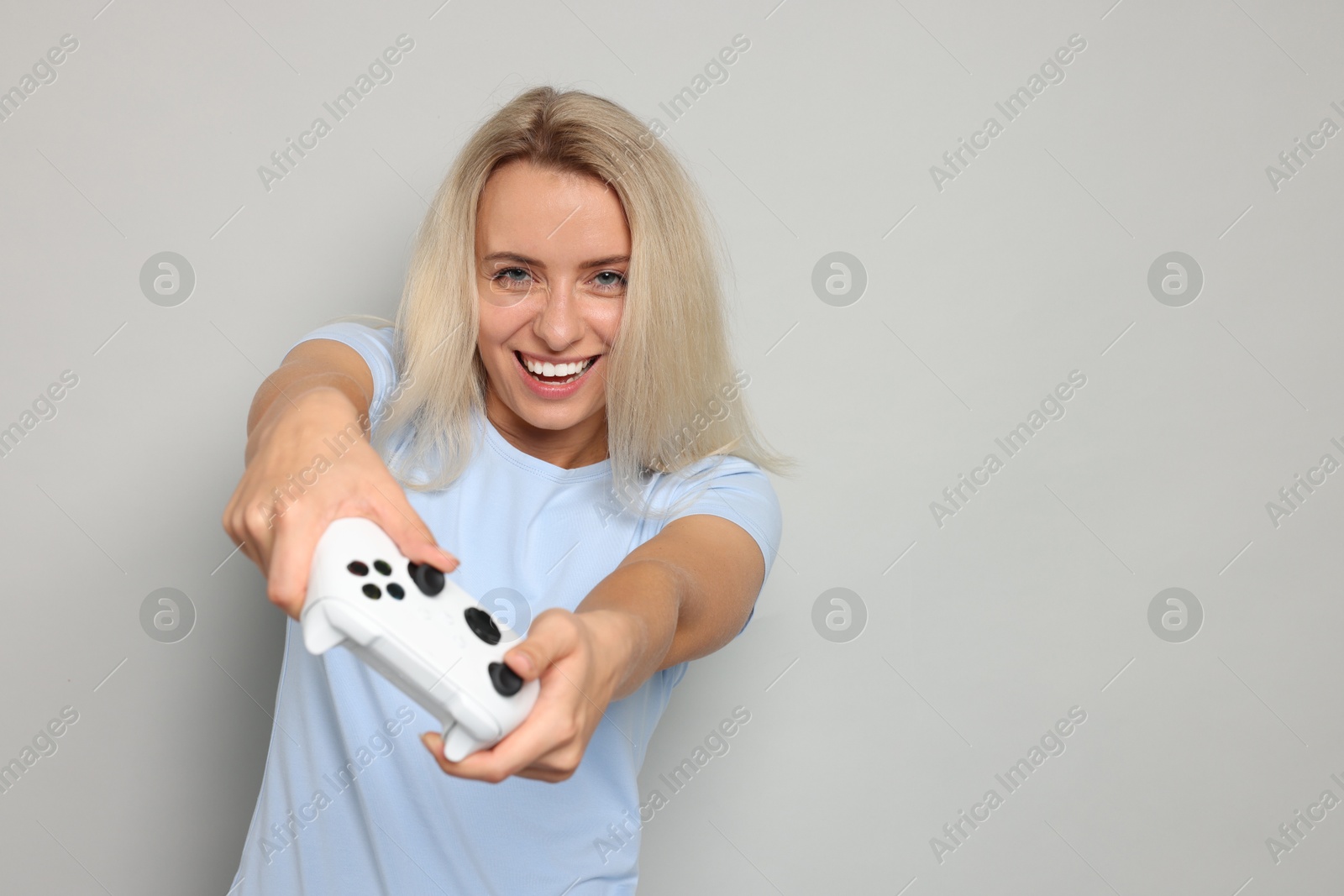 Photo of Happy woman playing video games with controller on gray background, space for text