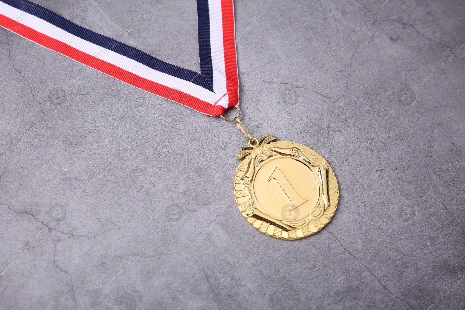 Photo of Golden medal with striped ribbon on grey background