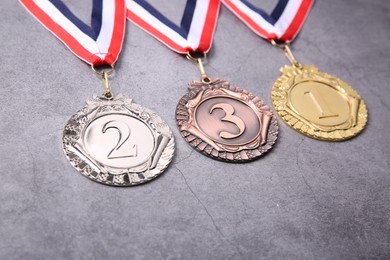 Photo of Golden, silver and bronze medals on grey background, closeup