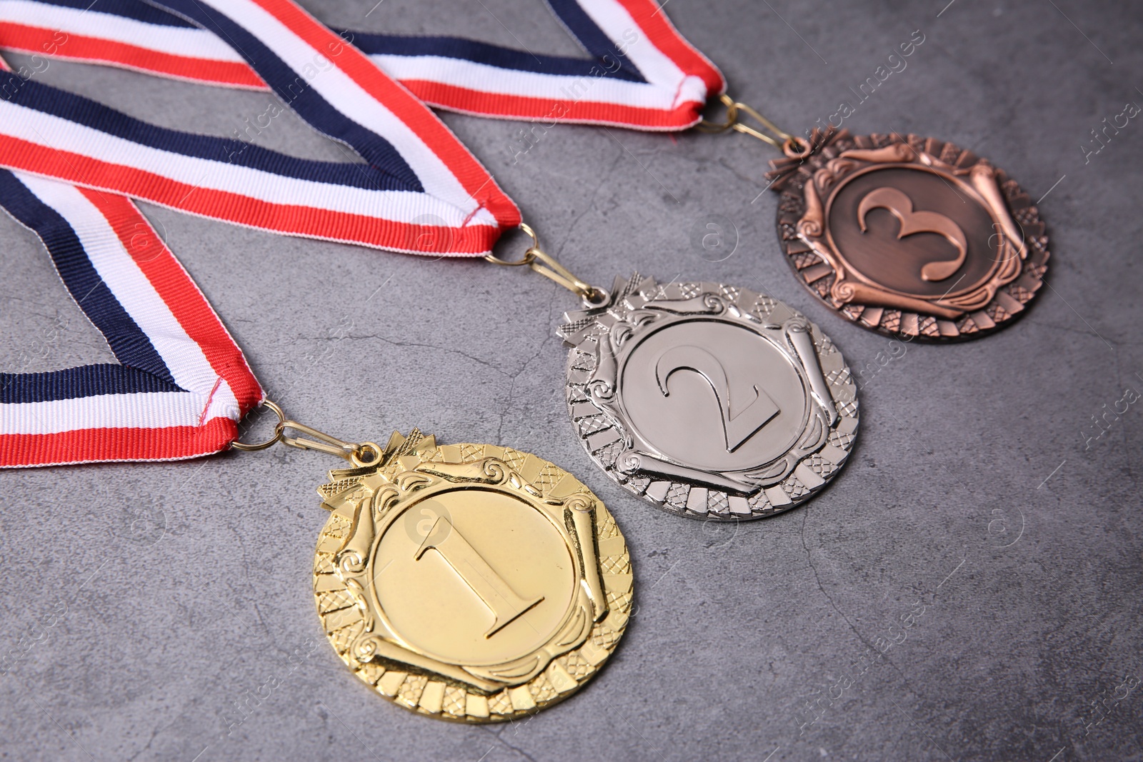 Photo of Golden, silver and bronze medals on grey background, closeup