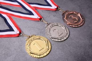 Photo of Golden, silver and bronze medals on grey background, closeup