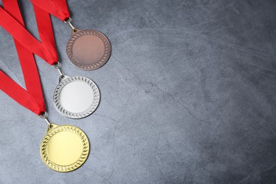 Photo of Golden, silver and bronze medals on grey background, above view. Space for text