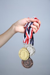 Photo of Woman with different medals on grey background, closeup