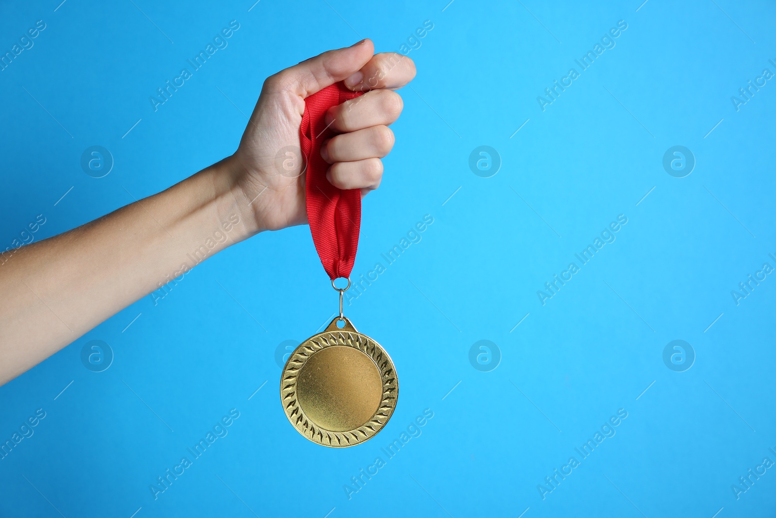 Photo of Woman with golden medal on light blue background, closeup. Space for text