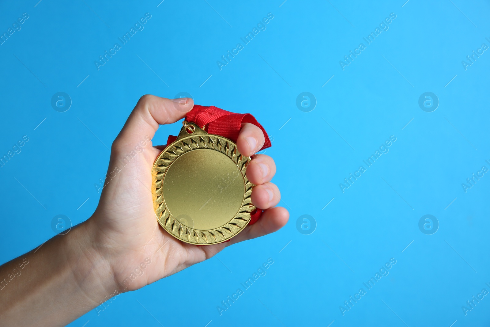 Photo of Woman with golden medal on light blue background, closeup. Space for text