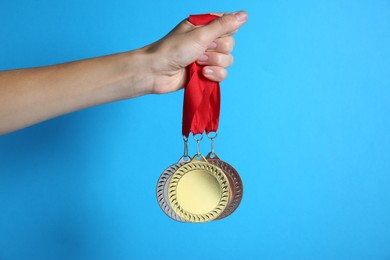 Photo of Woman with different medals on light blue background, closeup