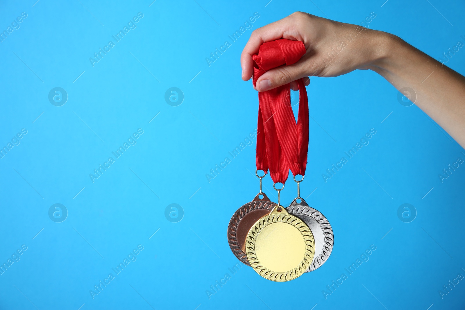 Photo of Woman with different medals on light blue background, closeup. Space for text