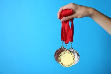 Photo of Woman with different medals on light blue background, closeup. Space for text