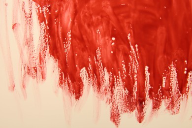 Red blood on beige background, top view