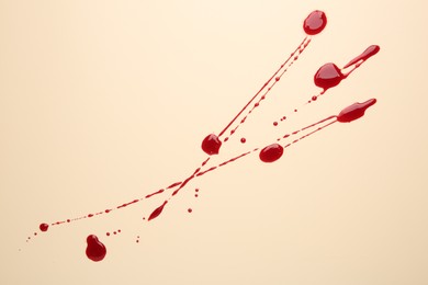 Splashes of blood on beige background, top view