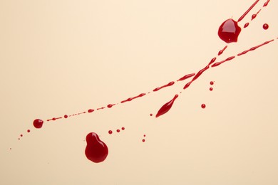 Photo of Splashes of blood on beige background, top view