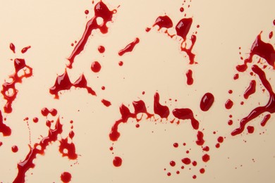 Photo of Splashes of blood on beige background, top view