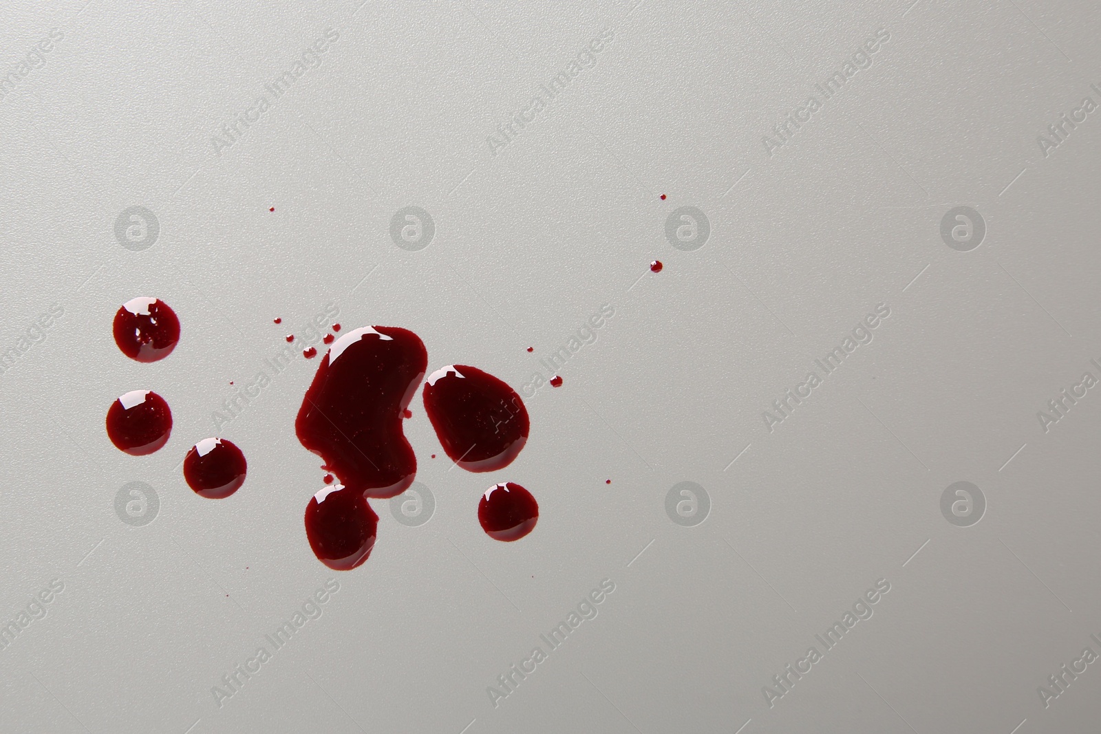 Photo of Drops of blood on light grey background, top view. Space for text