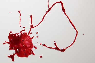 Photo of Splashes of blood on light grey background, top view