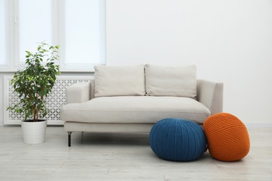 Photo of Comfortable couch and poufs in living room. Interior design