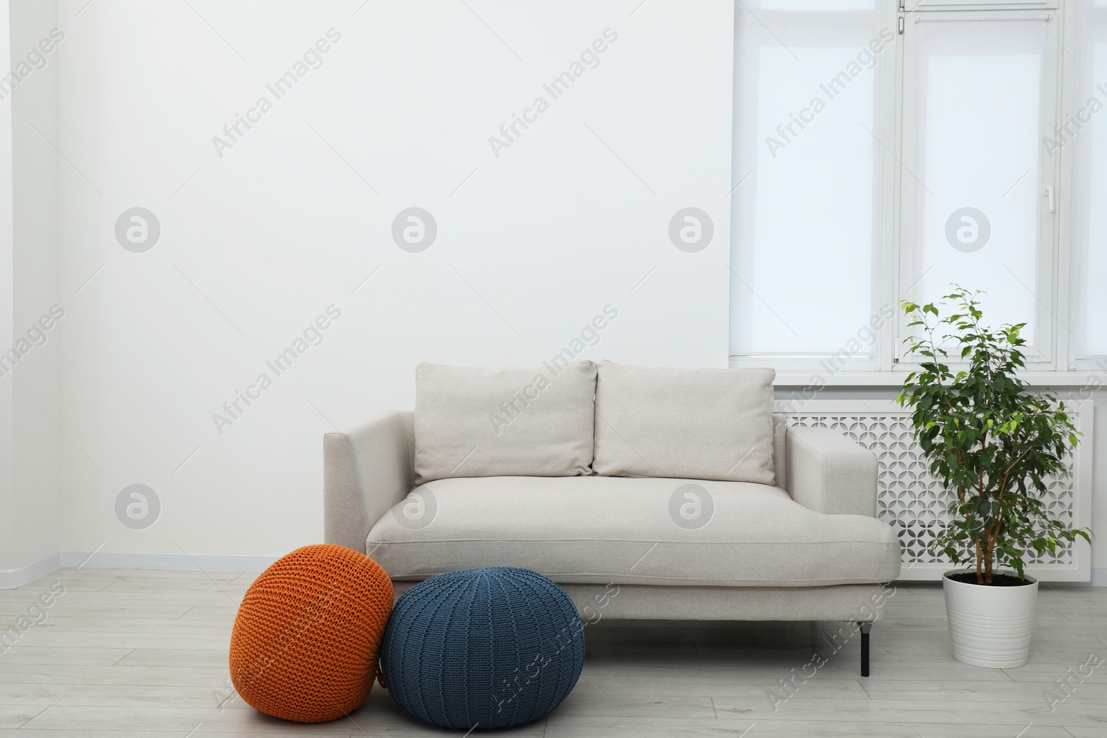 Photo of Comfortable couch and poufs in living room. Interior design