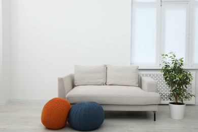 Photo of Comfortable couch and poufs in living room. Interior design