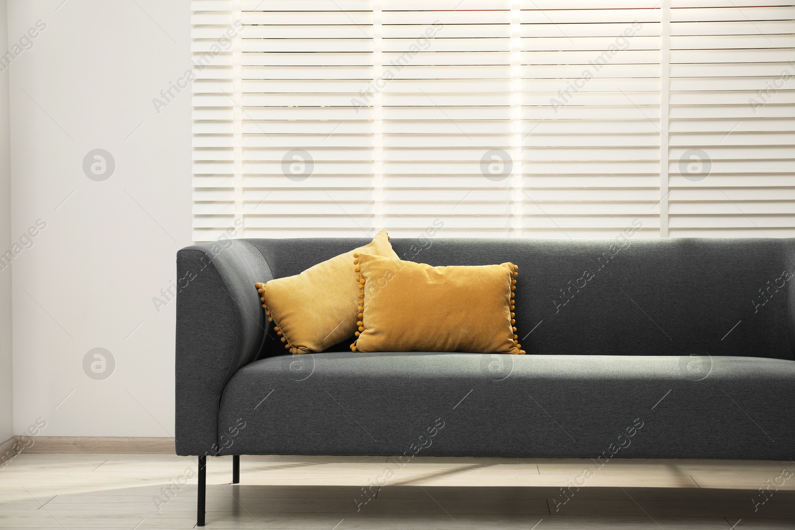 Photo of Comfortable couch with pillows near light wall indoors. Interior design